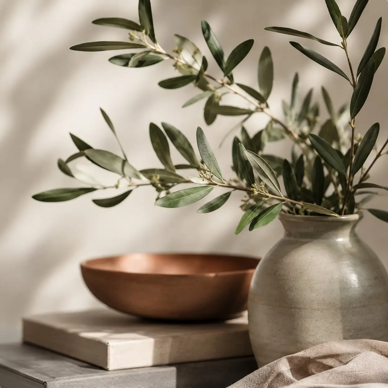 Close-up of an olive branch in a stoneware vase next to a copper bowl